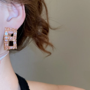 Close-up of 18K gold plated earring featuring square hollow pendant with zircon crystals