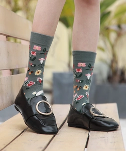 Detail of gray-green crew socks with vibrant floral patterns worn in an outdoor setting