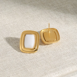 Macro view of gold stainless steel rectangular stud earrings with white enamel inlay