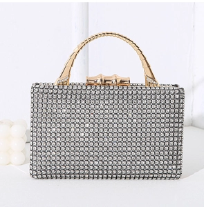 Close-up of sparkling silver rhinestones and golden bamboo metal handle on evening clutch