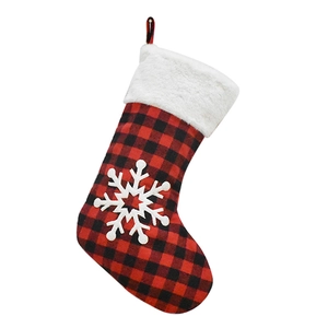Close-up of red and black buffalo plaid Christmas stocking with white faux fur and snowflake