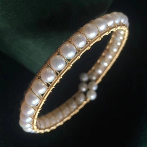 Close-up of handmade freshwater pearl bracelet with intricate gold wire wrapping detail