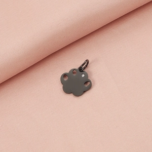 Close-up of black metal paw pendant with a clear crystal on pink textured background