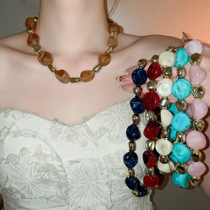 Close-up of colorful irregular acrylic beads necklace set with golden metal spacers