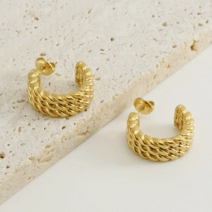 Detail view of 18k gold C-shape twisted hoop earrings on minimalist stone base