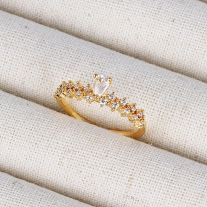 Close-up of a pear-cut clear gemstone ring with small diamonds on a gold-plated band