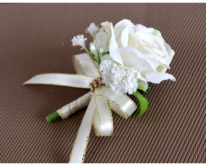Detail of white artificial rose boutonniere with gold ribbon and rhinestone accents