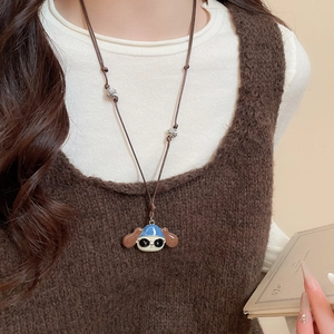 Close-up of a cartoon dog pendant necklace with a blue hat and brown woven rope strap