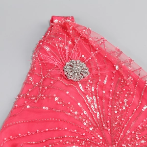 Detail of sequins, white pearls, and rhinestone brooch on pink sleeveless evening dress