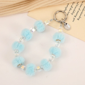 Detail of blue faux fur pom poms and clear faceted beads on a stylish wristlet keychain