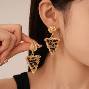 Macro shot of geometric triangular leopard print earrings with textured golden metal edges