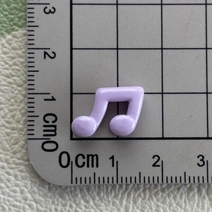 Mini violet resin music note charm for DIY crafts measured on a metric scale ruler