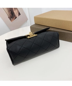 Dettaglio di borsa in pelle nera trapuntata con chiusura in metallo dorato