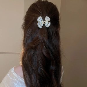 Dettaglio di un elegante fermaglio per capelli a farfalla con zirconi su capelli mossi