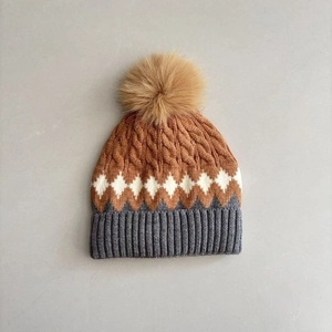 Macro detail of tricolor diamond knit pattern and fluffy pompom on winter toddler hat