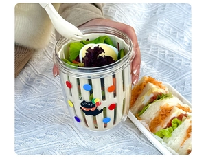 Detail of portable salad cup with built-in drainer and spoon on picnic blanket