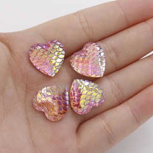 Detailed view of four pink resin heart charms with fish scale texture and AB iridescent finish