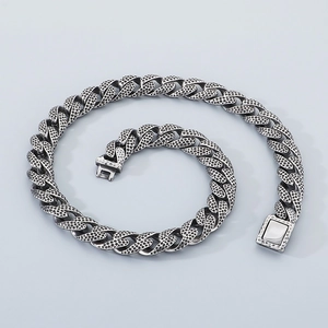 Macro detail of vintage spotted Cuban link chain with textured surface and buckle