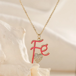 Macro shot of gold-plated Fe letter pendant with rose red glaze and heart rhinestone