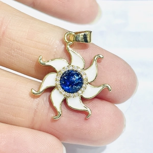 Detail of gold starburst pendant with white enamel, blue stone and zircon inlay