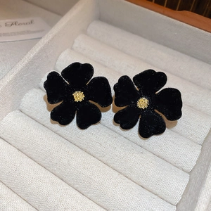 Close-up of black velvet flower earrings with golden centers in a premium display box
