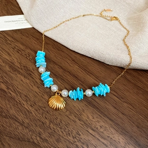Macro detail of starfish and pearl pendant necklace with turquoise beads on linen fabric