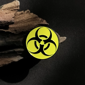 Biohazard metal badge brooch with yellow and black enamel finish on dark wood