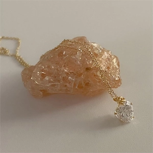 Detail of heart-cut zircon pendant with 18K gold O-chain on natural gemstone