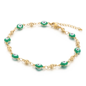 Gold stainless steel evil eye bracelet with green enamel beads in a minimalist flat lay