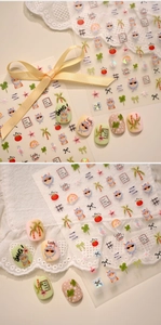 Detailed view of lucky clover and cute cat nail stickers on artificial nail tips