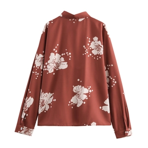 Détail de la chemise rouge brique à manches longues avec motifs floraux et coupe au dos