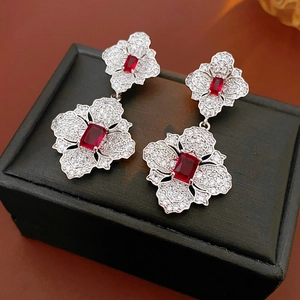 Macro detail of silver floral earrings with red rectangular gemstones in black jewelry box