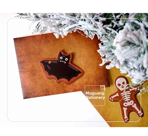 Detail of bat and gingerbread skull tags on vintage card with winter festive pine decor