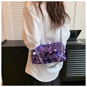 Detail of purple sequin handbag with thick silver chain strap on model's shoulder
