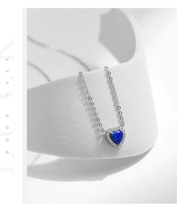 Close-up of heart-shaped blue opal pendant necklace with sparkling white zircon halo