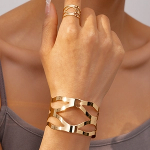 Gros plan sur un ensemble bracelet et bague géométrique doré avec finition polie sur modèle