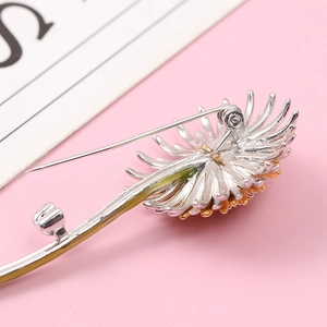 Daisy flower brooch in silver and gold plating with pin back on a pink background
