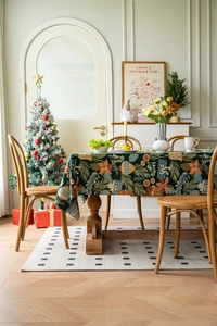 Close-up of dark green Christmas tablecloth with poinsettia and pine branch patterns