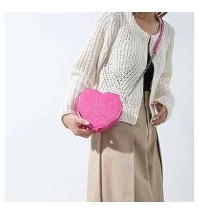 Detalle de bolso corazón rosa con costuras de telaraña blanca y correa de cadena metálica