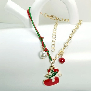 Detail of Christmas bracelet with red enamel stocking charm and green braided rope
