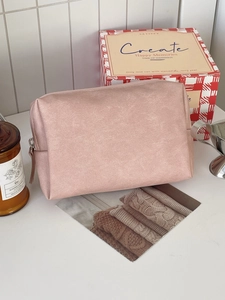 Pink waterproof PU leather cosmetic bag with zipper in a cozy minimalist home setting