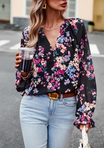 Dettaglio di blusa a maniche lunghe con scollo a V e fiori rosa su fondo nero