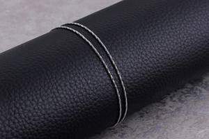 Detailed macro shot of silver minimalist snake chain wrapped on a black leather display