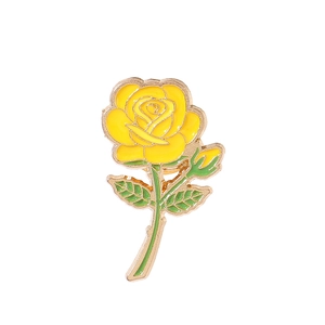 Detailed view of an elegant yellow rose brooch with green leaves and gold metal edges