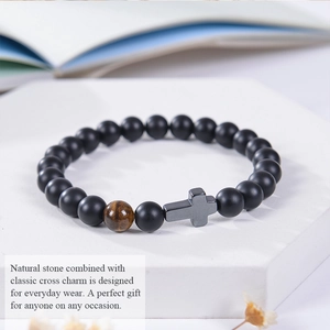 Detail of matte black beads with tiger eye stone and cross charm on a display stand
