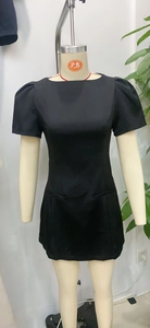 Détail d'une robe courte noire avec des manches bouffantes plissées et un col rond chic