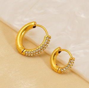 Detail of 18K gold stainless steel earrings with sparkling cubic zirconia on marble