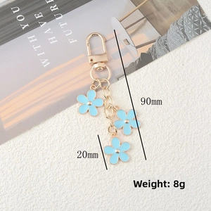 Detail view of gold flower keychain with three blue charms showing 90mm total length