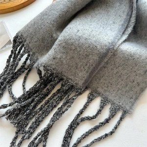Detail shot of grey winter scarf texture and dark grey fringe on a white surface