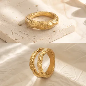 Dettaglio di anelli in acciaio al titanio placcati oro 18K con trama martellata e zircone